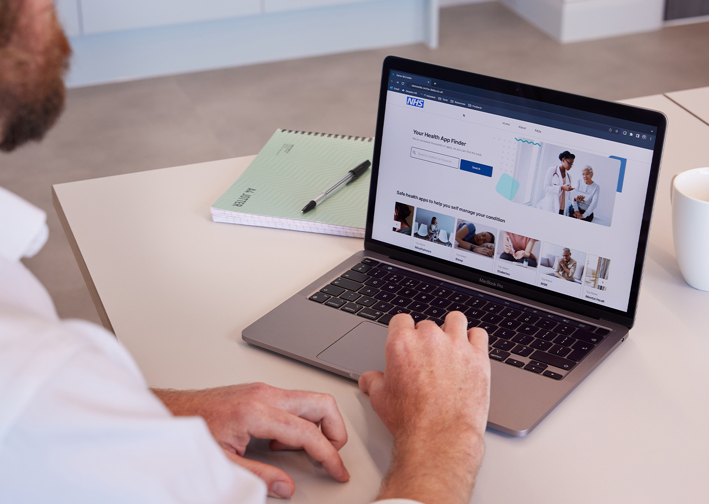 GP looks at ORCHA Health App Library on a laptop